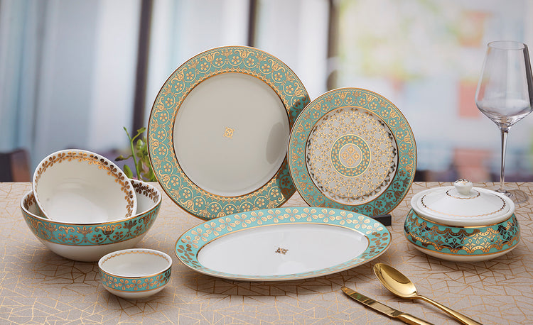 Oman Collection 22-piece dinner set with rich gold embellishments on teal green, includes plates, bowls, and platter.